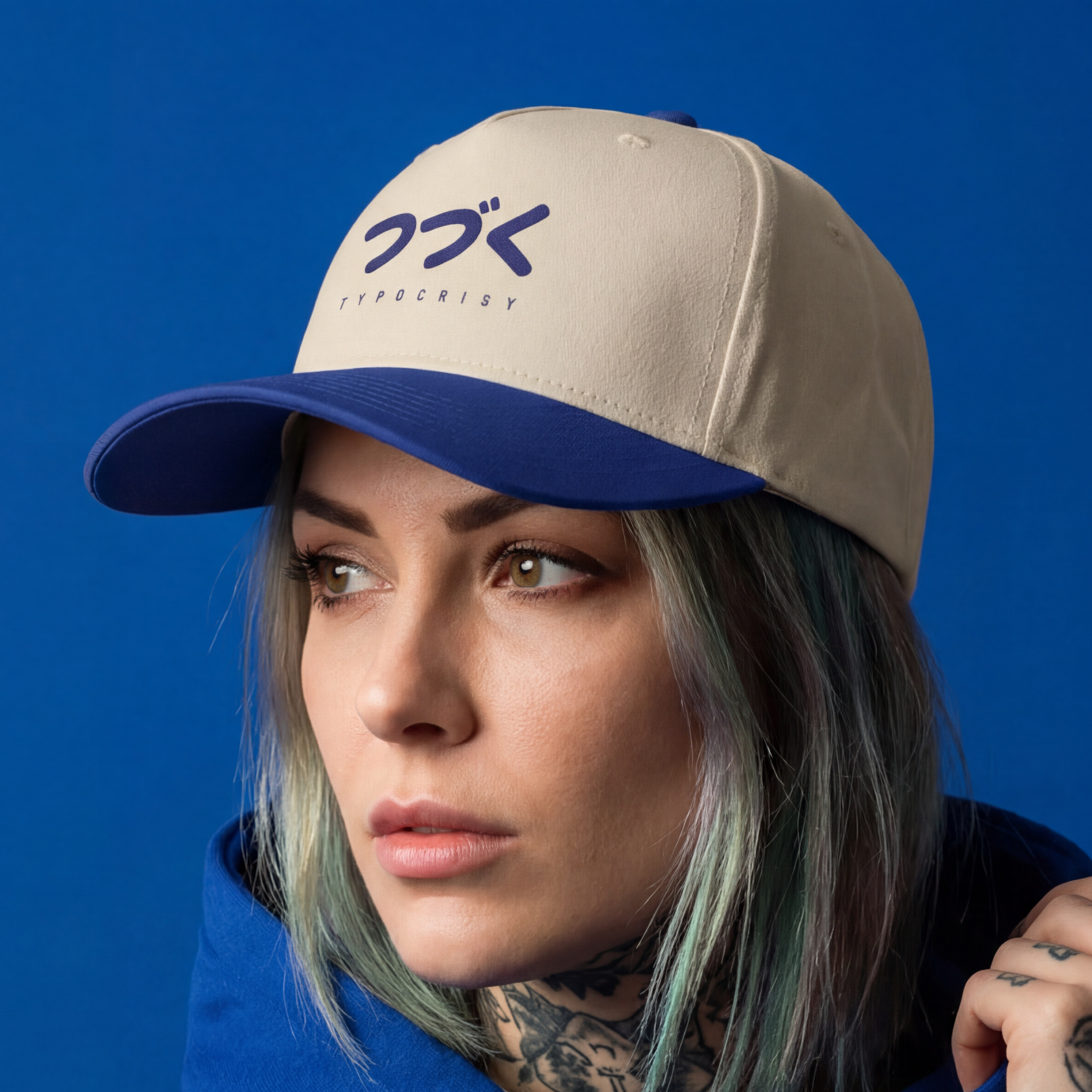 Person wearing a beige and blue cap with a logo against a blue background