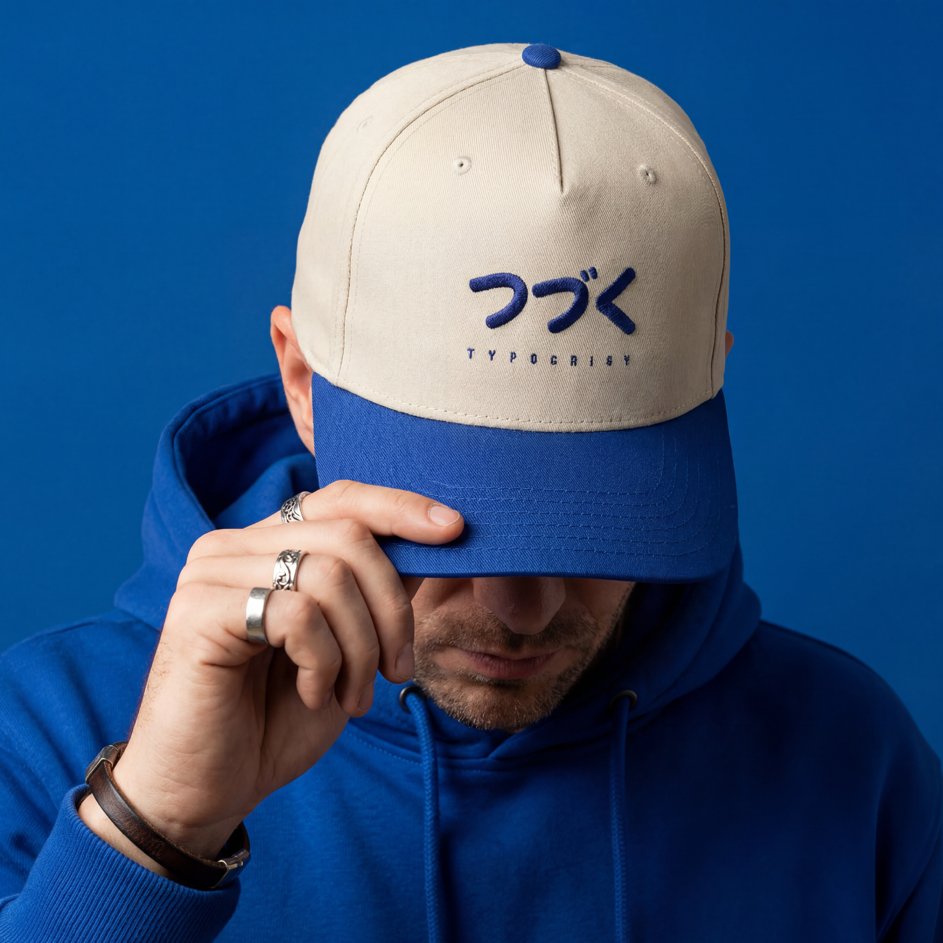 Person wearing a beige and blue cap with a logo on a blue background