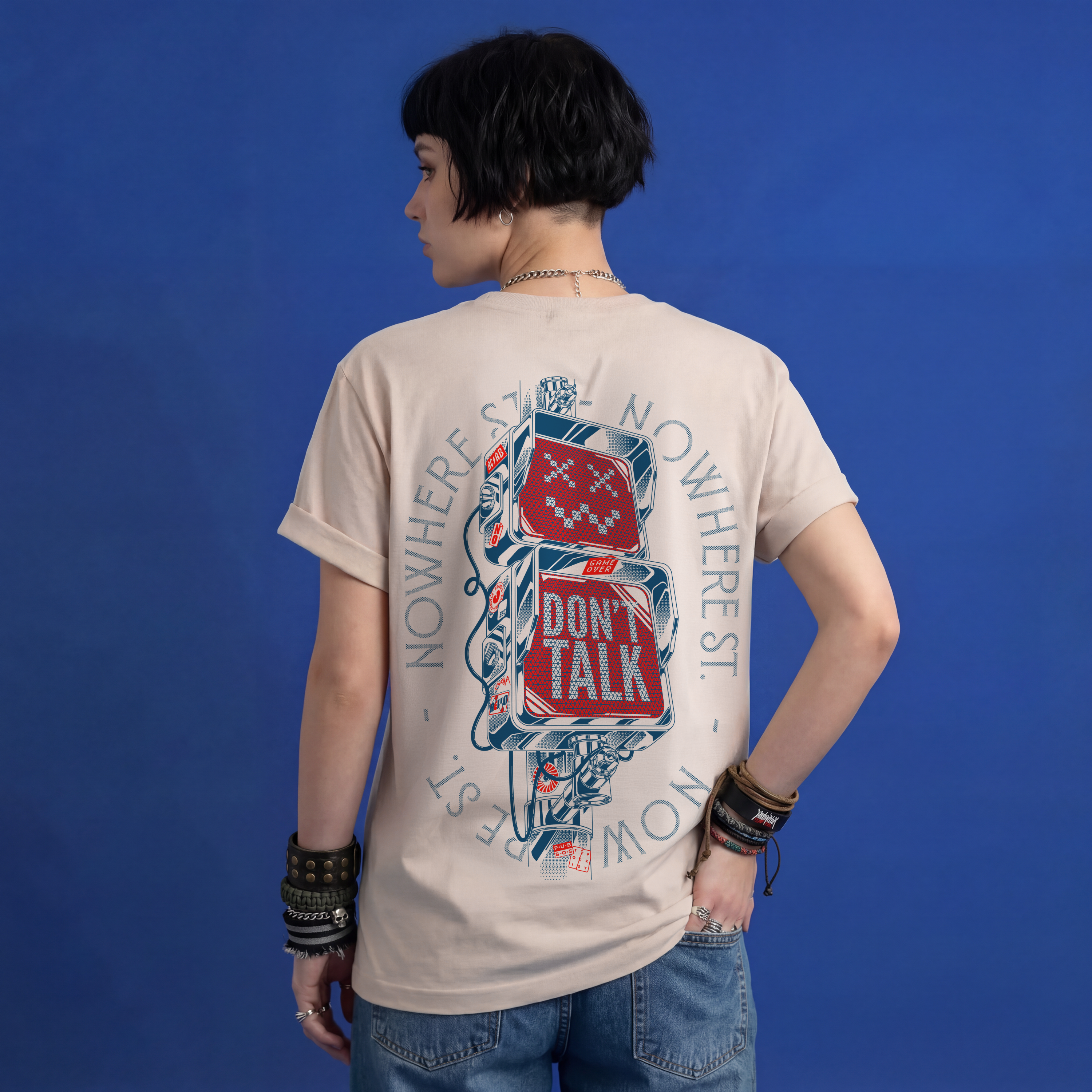 Female model wearing beige Typocrisy Don't Talk oversized t-shirt, back graphic, blue studio background