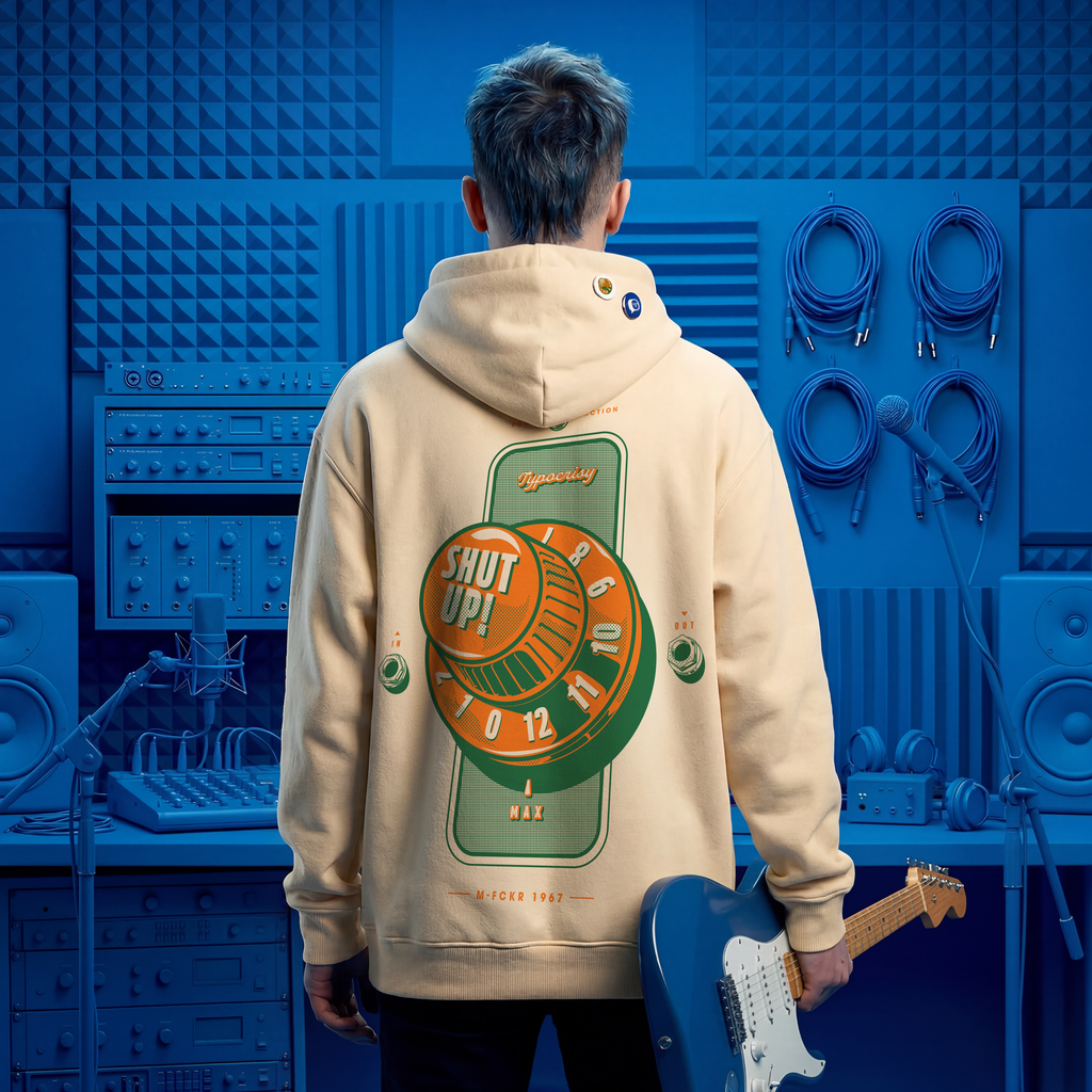 Person wearing a beige hoodie with a graphic design, holding a blue electric guitar in a blue-themed room.