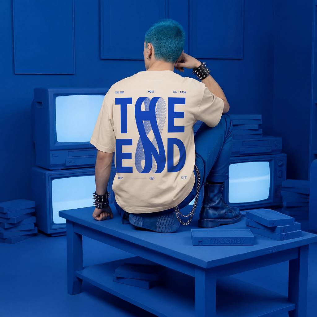 Person sitting on a blue platform with multiple vintage TVs, wearing a beige t-shirt with 'Take End' text.