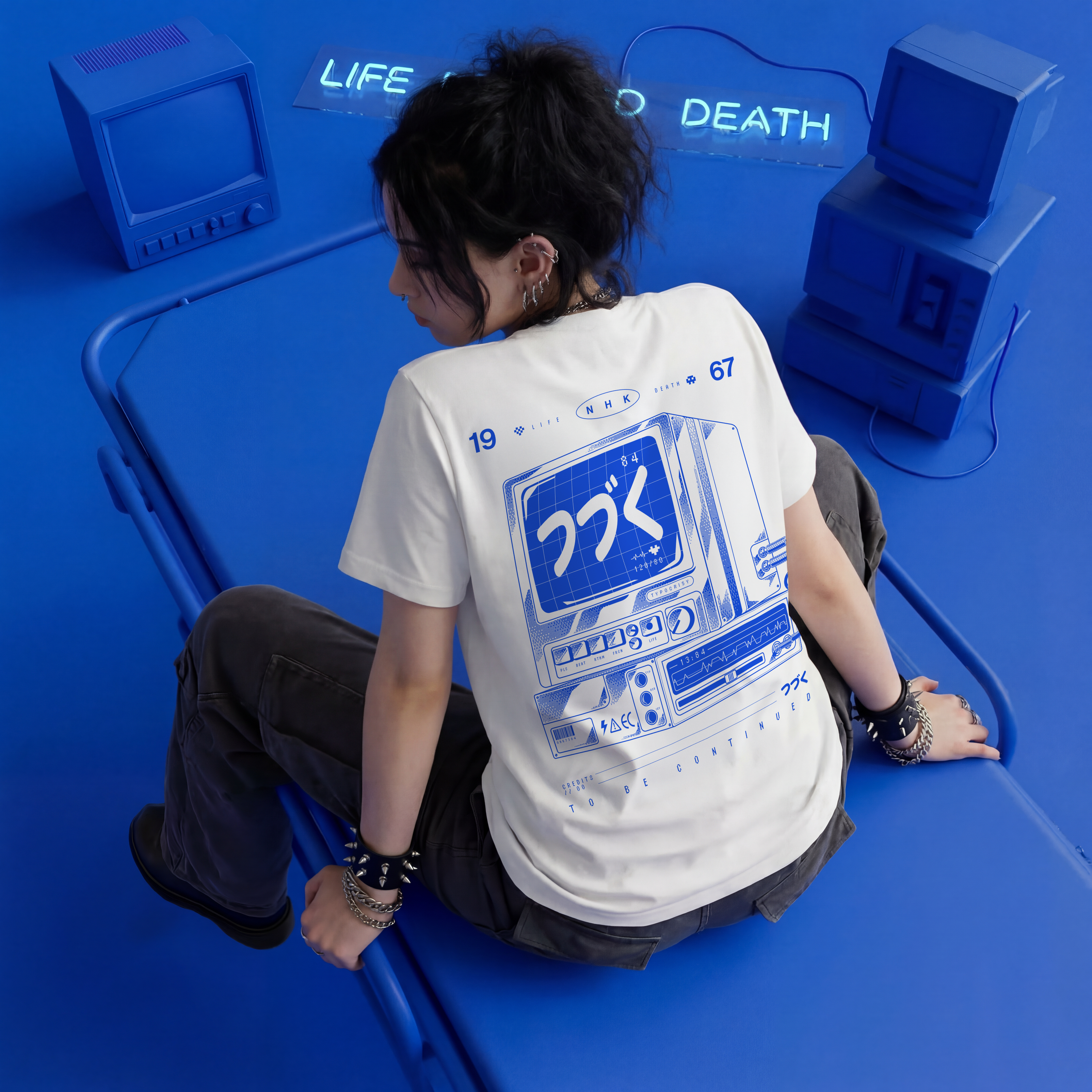 Person wearing a white t-shirt with blue graphics sitting on a blue chair with 'LIFE' and 'DEATH' text in the background.