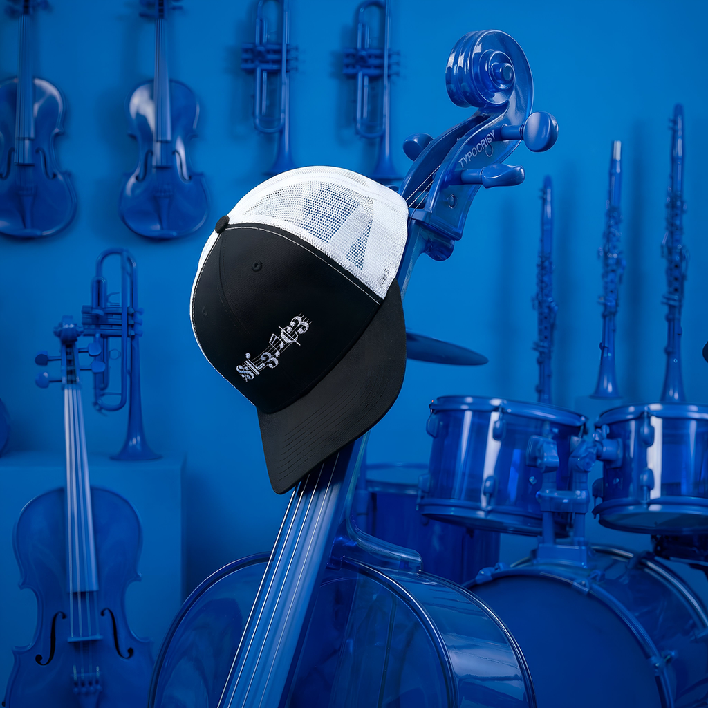 Cello with a Typocrisy SIL3NC3 Embroidered Trucker cap featuring musical notes against a blue background with musical instruments.