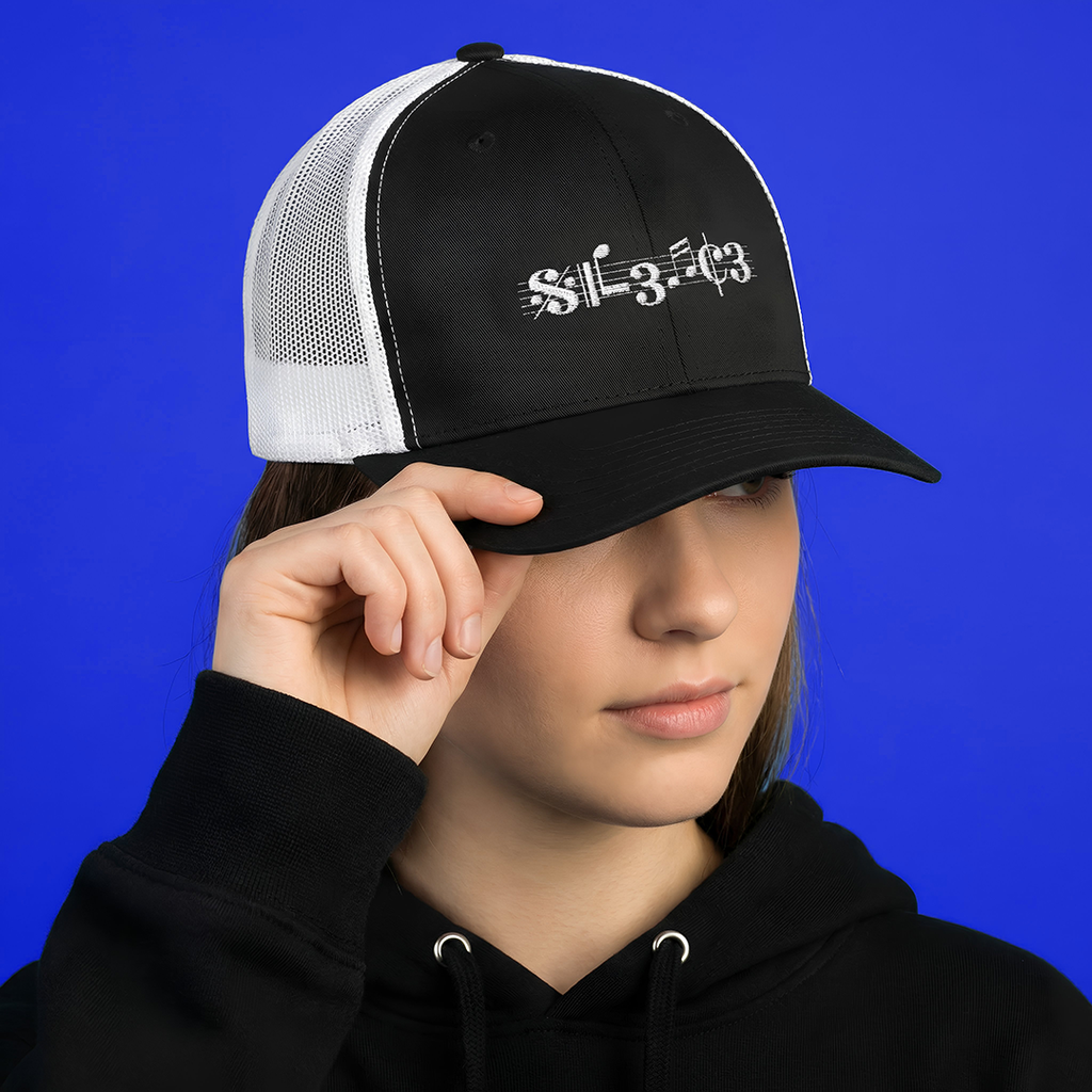 Person wearing a black and white Typocrisy SIL3NC3 Embroidered Trucker cap with musical notes design on a blue background